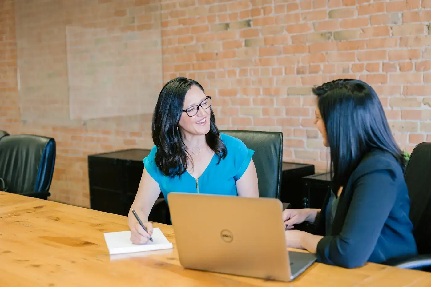 Two people talking across a meeting table
