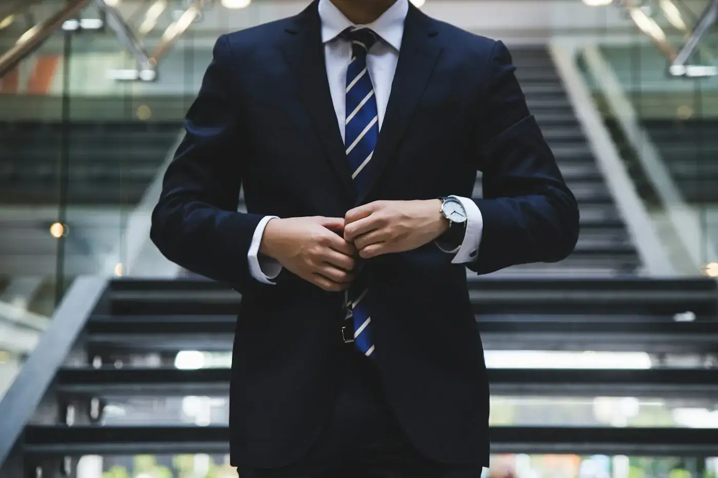 A person in a suit buttoning their jacket